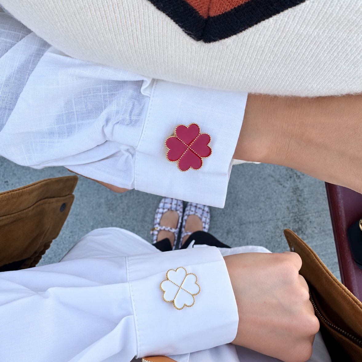 Two white dress shirts shown with decorative four-leaf clover button covers, one in red and one in white