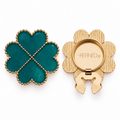 A four-leaf clover-shaped gold-tone decorative button cover with deep teal-green heart-shaped sections and a gold-dotted outline, shown closed and open on a white background. Refined by JV branding is visible on the back beside the clip-on clasp mechanism