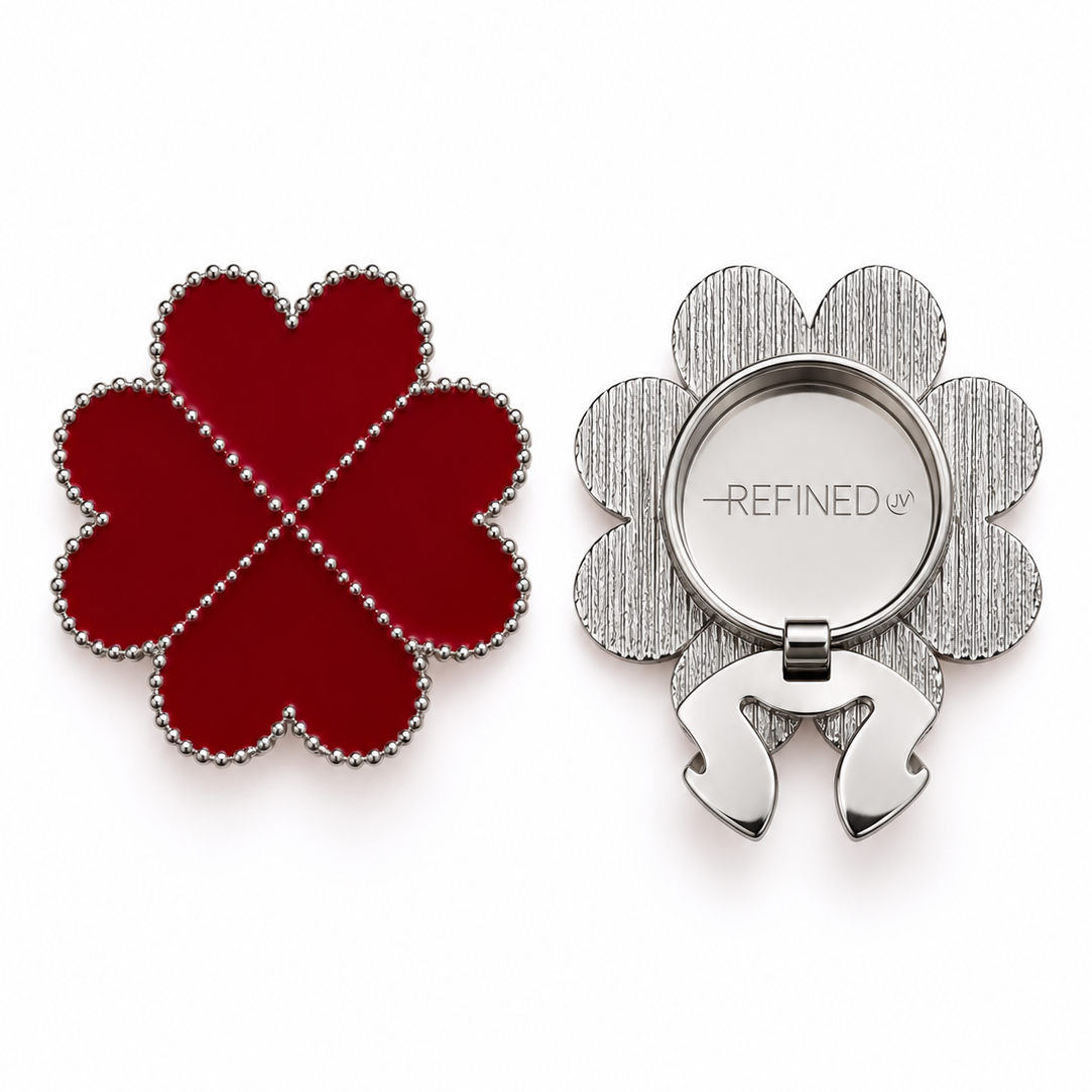 A four-leaf clover-shaped silver-tone decorative button cover with deep red heart-shaped sections and a silver-dotted outline, shown closed and open on a white background. Refined by JV branding is visible on the back beside the clip-on clasp mechanism