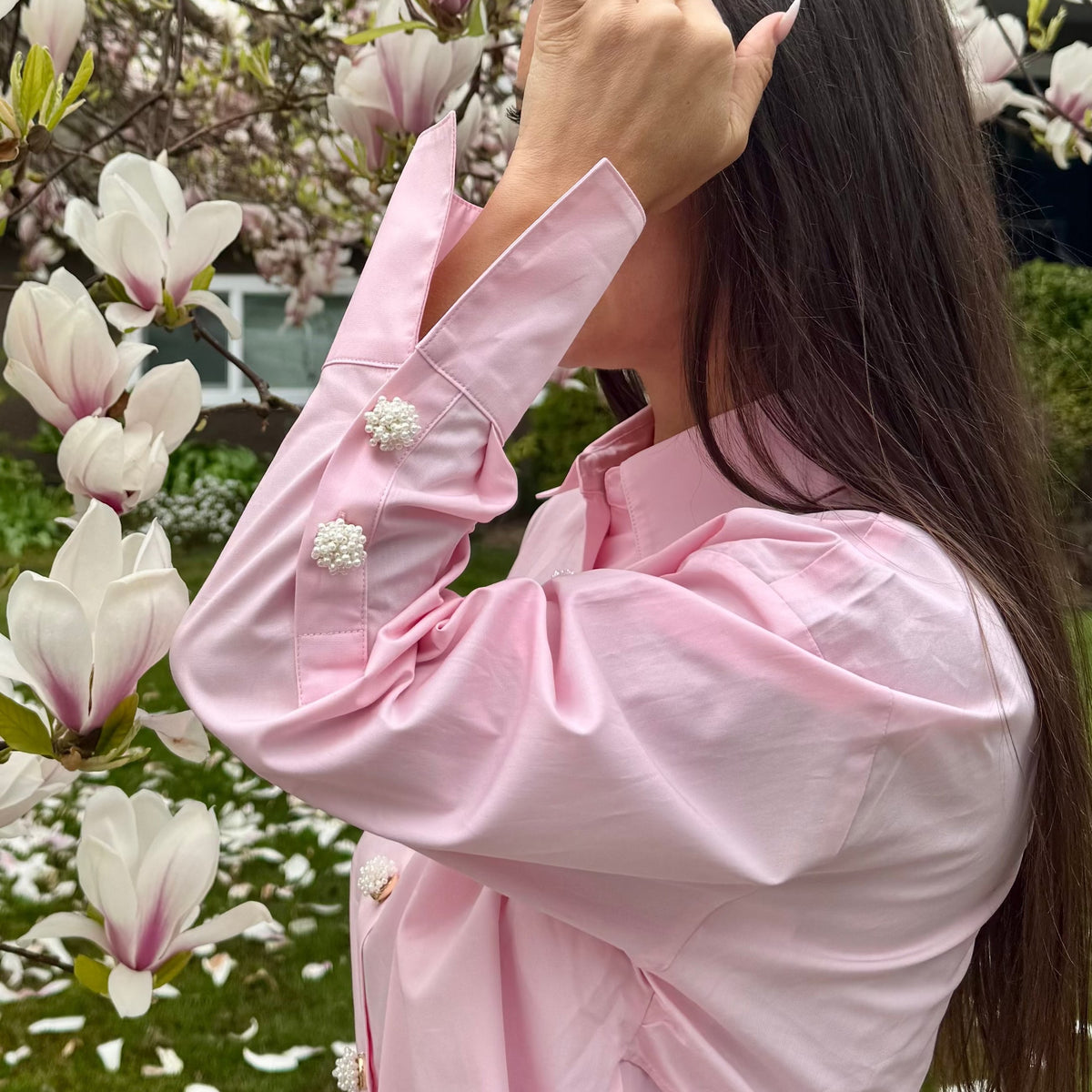 Refined by JV ivory pearl button covers on a light pink shirt sleeve, worn by a woman near blooming magnolia trees.