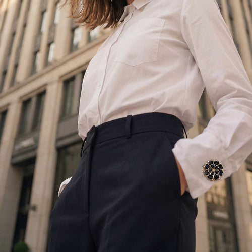 Refined by JV Camélia button cover with black petals and gold-tone crystal center worn on a white shirt cuff