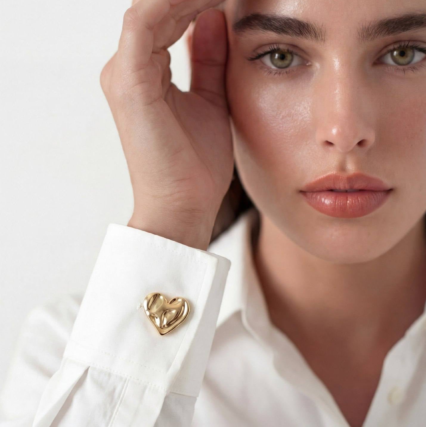 Refined by JV Aurelia heart-shaped gold-tone button cover attached to a white shirt cuff worn by a model