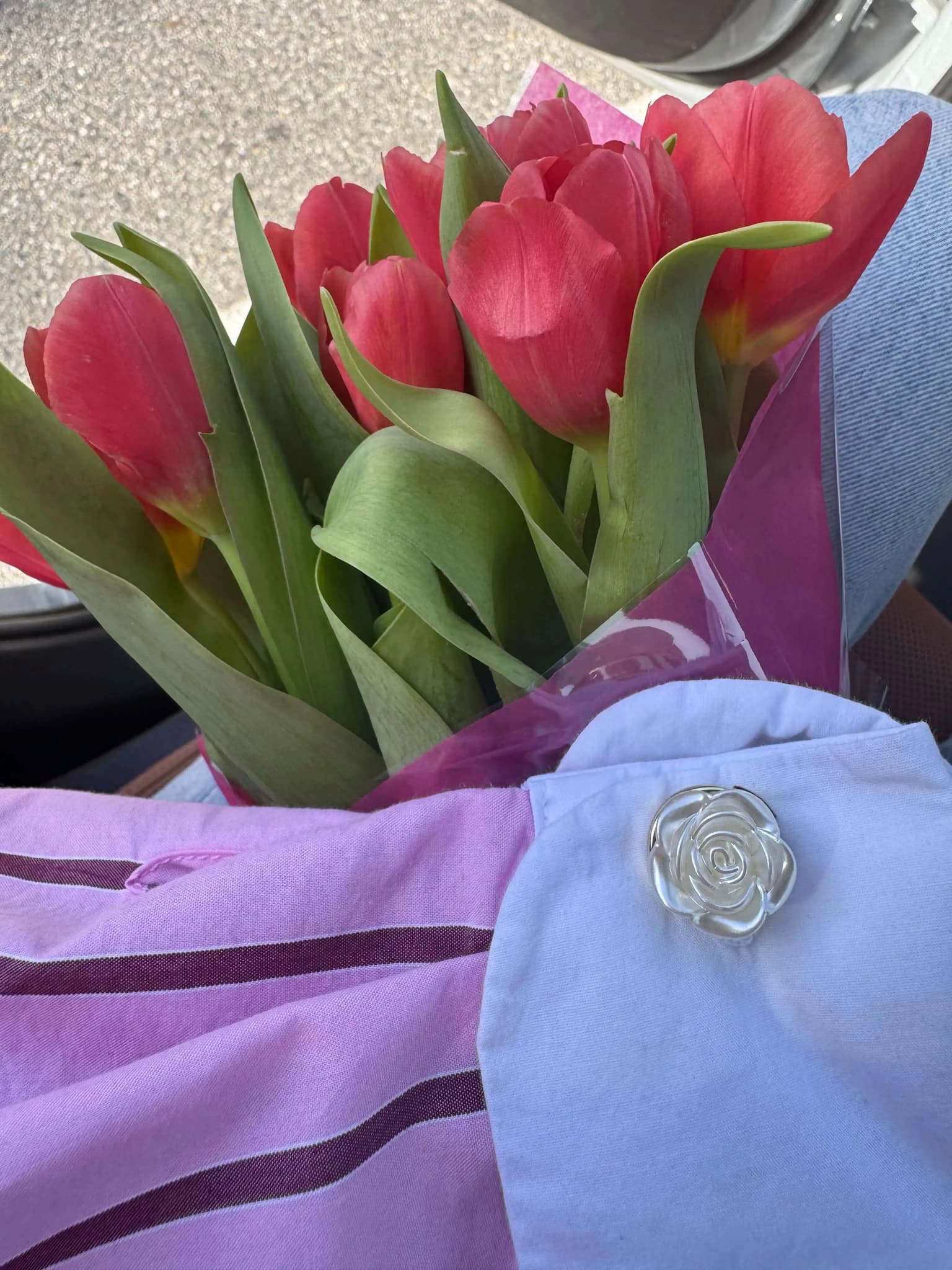 Refined by JV ivory rose button cover pinned to a white shirt collar next to a bouquet of red tulips