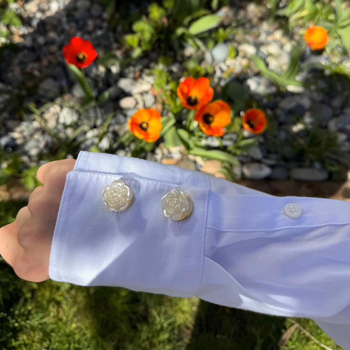 Refined by JV ivory rose button covers with gold-tone finish attached to a white shirt cuff in a garden setting