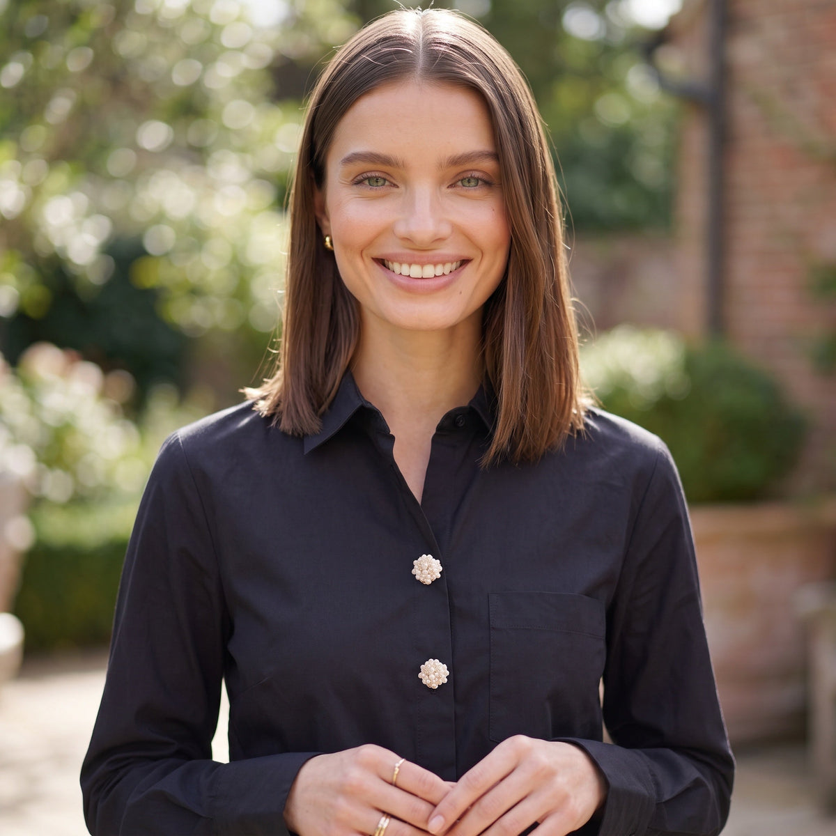 Refined by JV Ivory Sonata button covers in pearl and gold-tone worn on a black shirt by a smiling woman outdoors