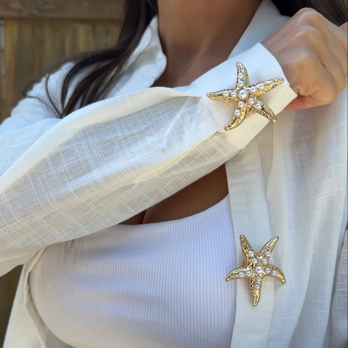 Refined by JV gold-tone starfish button covers with pearl accents worn on a white shirt cuff and lapel